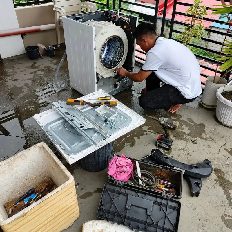 Technician repairing a front-load washing machine with the casing removed