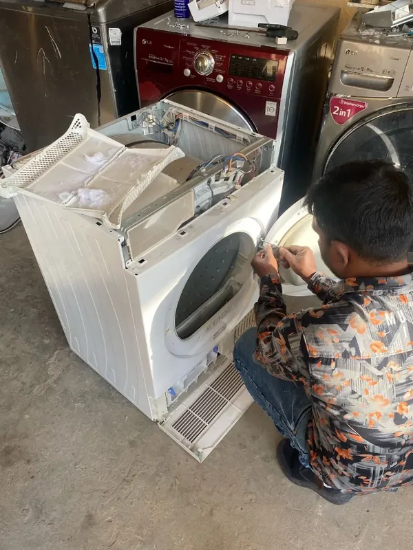 Technician working on a front-load washing machine with the front panel open