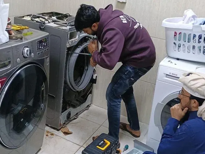 Technician repairing an LG front-load washing machine at a customer's home