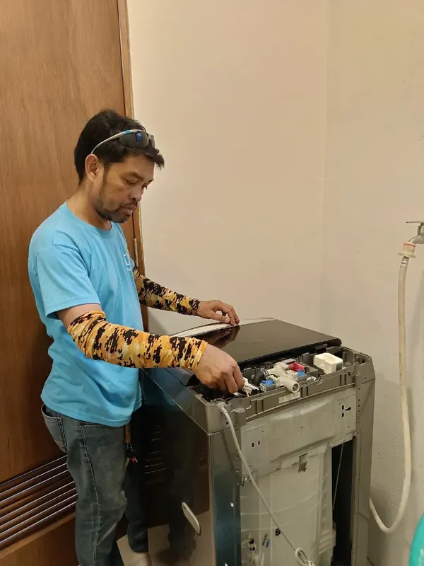 Technician repairing the control panel of a top-load washing machine