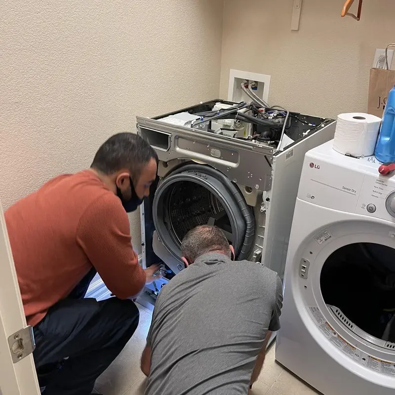 Two technicians servicing a front-load washing machine