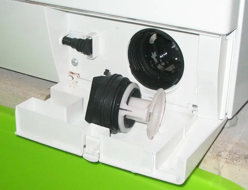Front-load washing machine with the drain pump filter cover open and the filter unscrewed