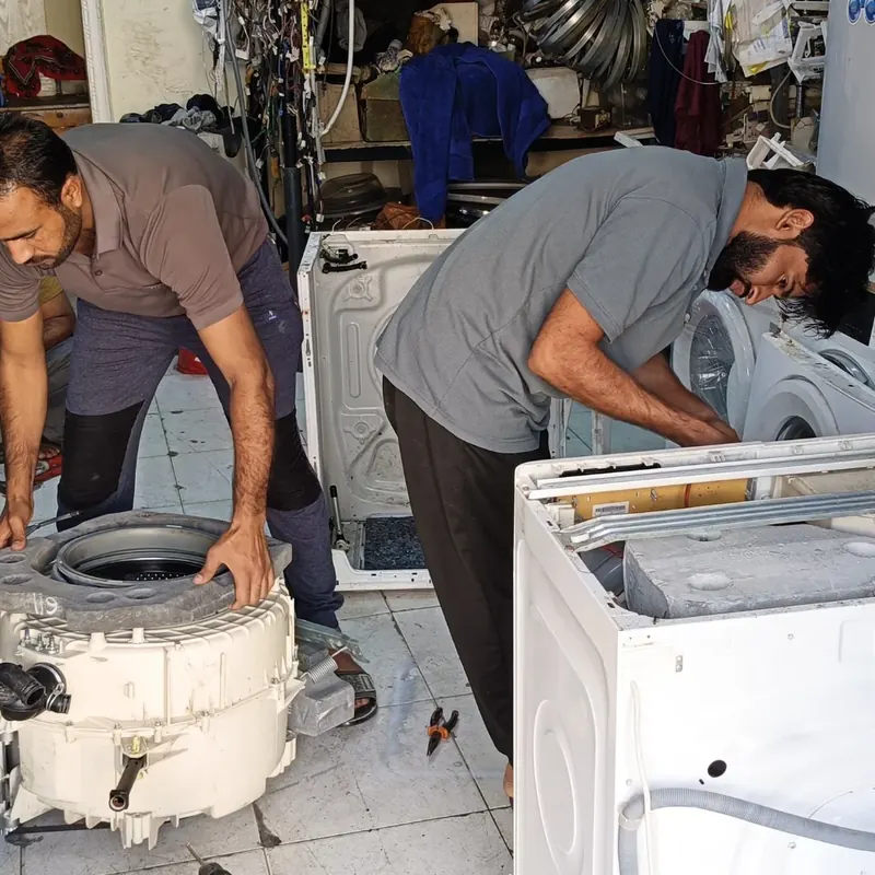 Technicians replacing the drum bearings of a front-load washing machine